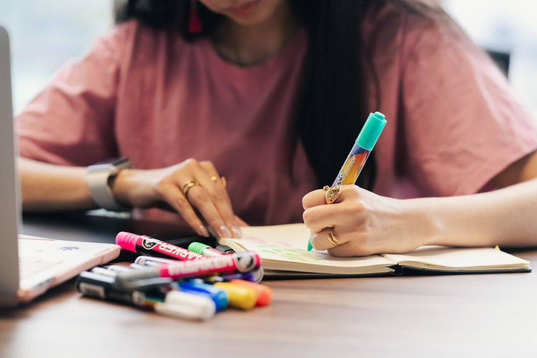 Person writing notes at a desk with a notebook and pen